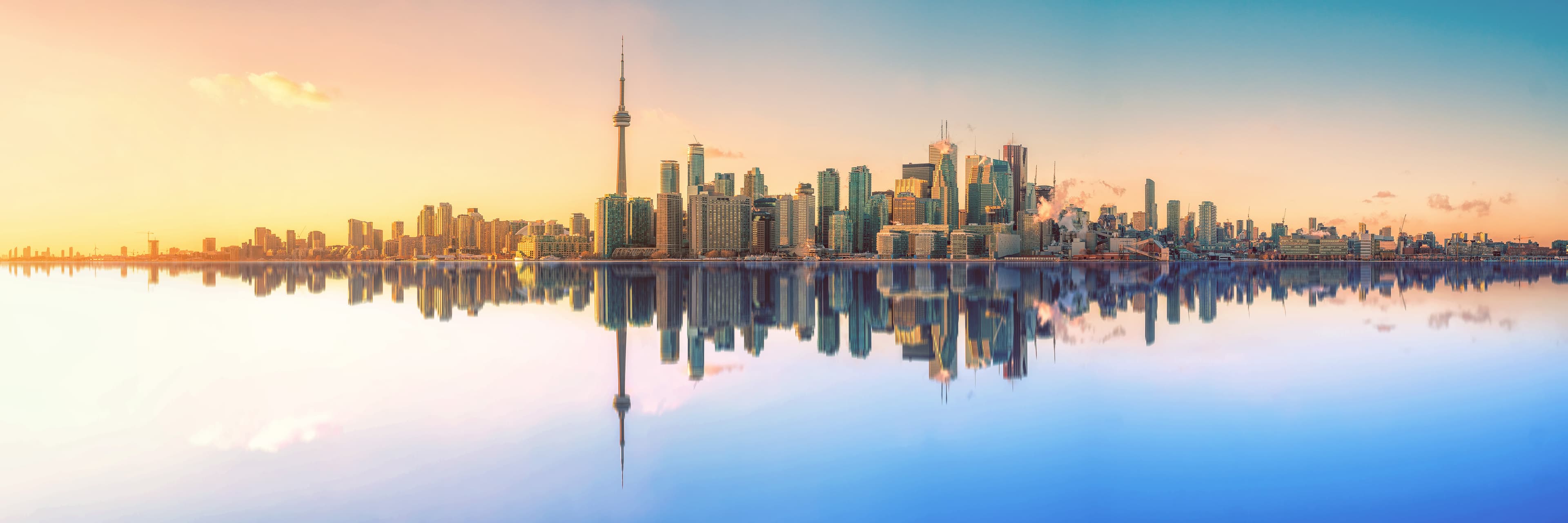 Toronto skyline at night with CN Tower and Rogers Centre illuminated, city lights reflecting on Lake Ontario